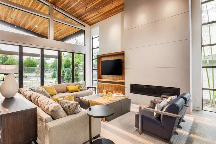 A luxurious open living space featuring a mounted flat-screen TV, couches, and large windows.