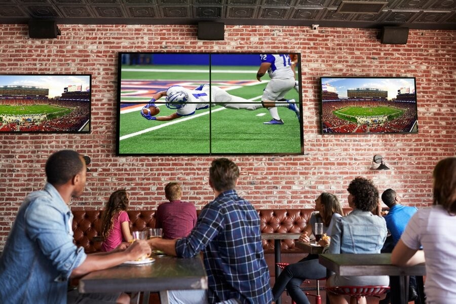 Several video wall displays showing football games at a restaurant.
