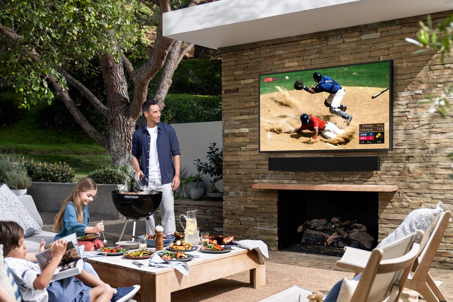 Image of man barbecuing with family while watching tv on Samsung Terrace